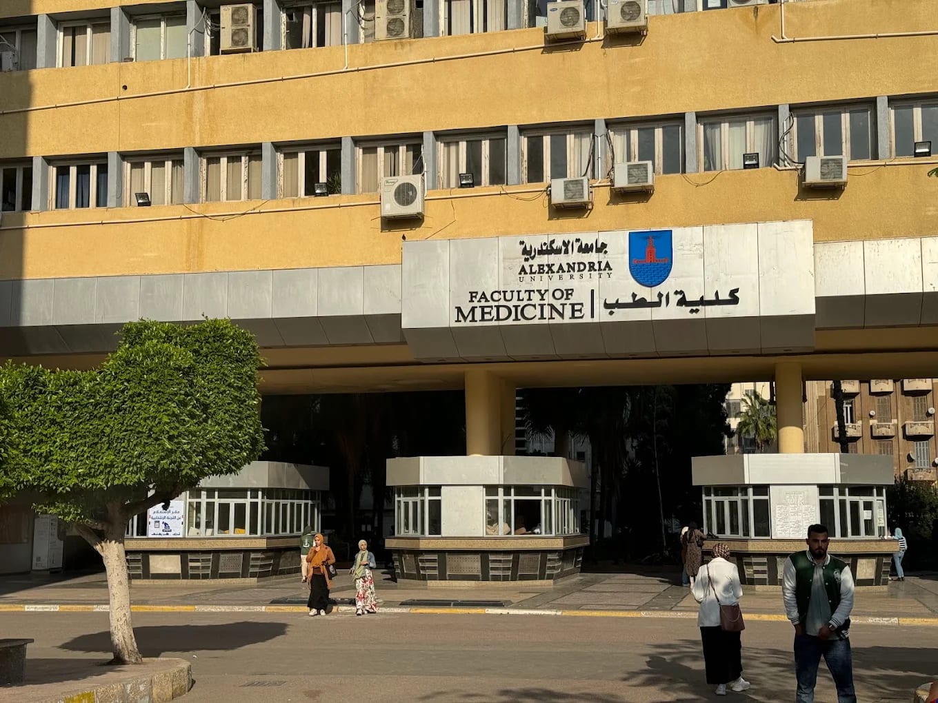 The Faculty of Medicine entrance at Alexandria University, with its English and Arabic signage and the Alexandria lighthouse emblem