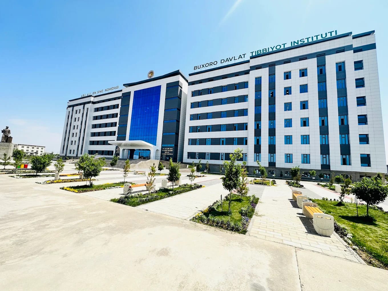 The modern facade of Bukhara State Medical Institute with its landscaped plaza and Avicenna statue