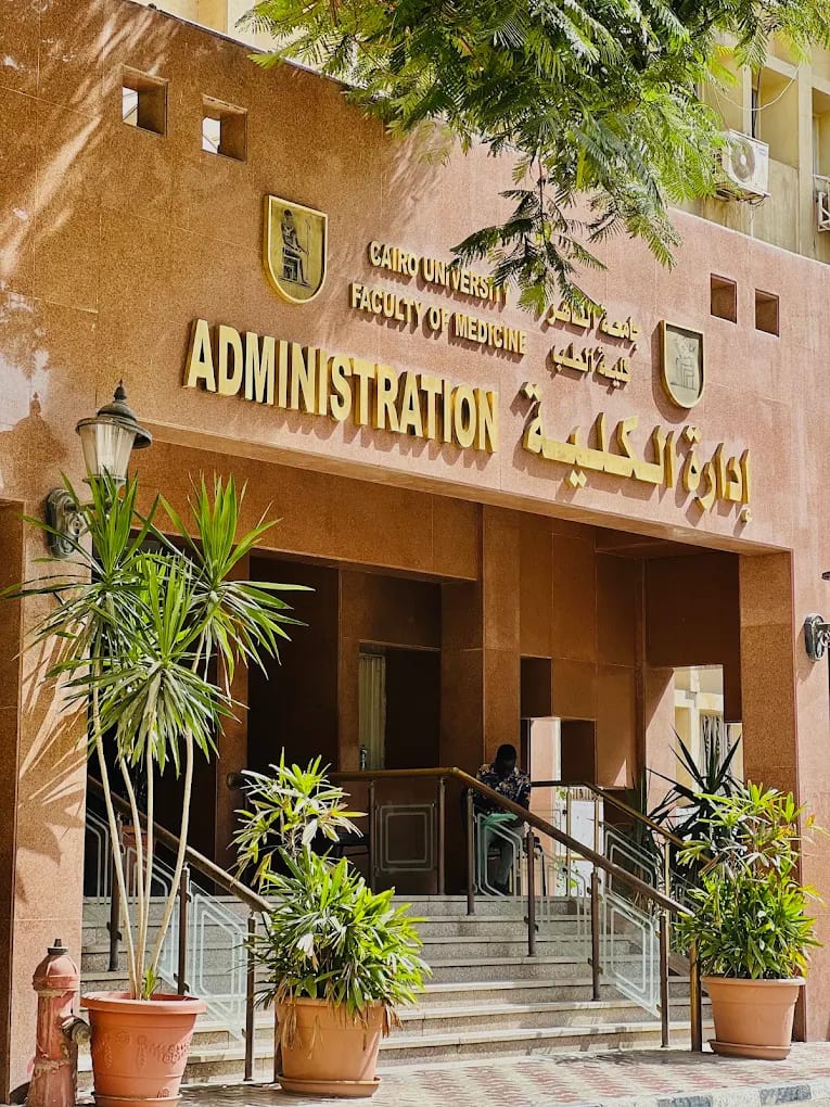 The entrance of the Cairo University Faculty of Medicine administration building, with its English and Arabic signage and the university emblem
