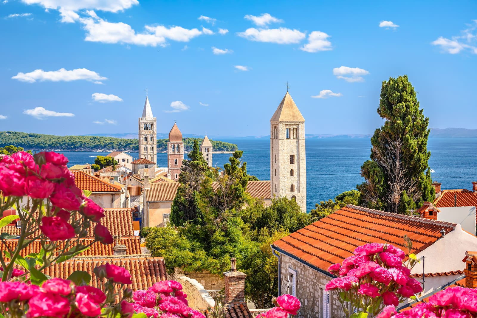 Bell towers of Rab old town above red rooftops and the Adriatic