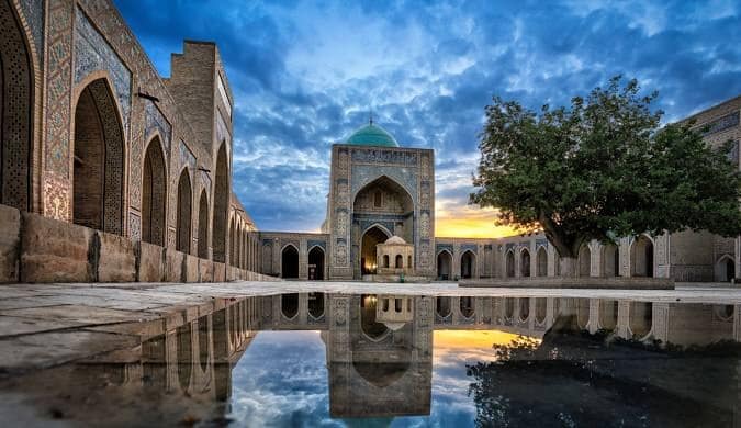 Kalyan Mosque courtyard reflected in water at sunset in Bukhara, Uzbekistan