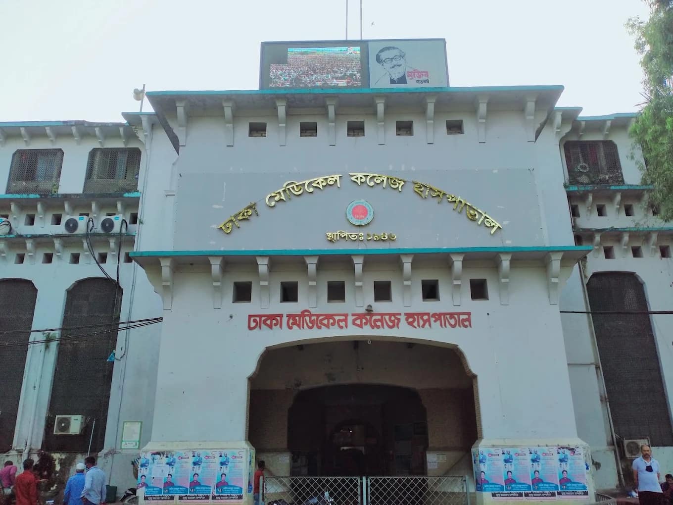 Main entrance of Dhaka Medical College Hospital with a large public display screen