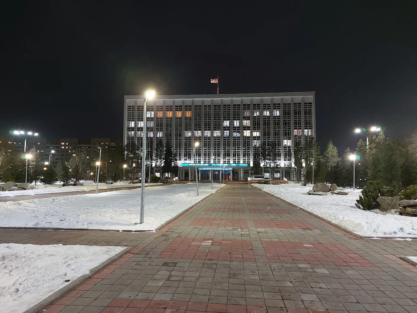 An academic block of Karaganda Medical University at night, with the Kazakh flag