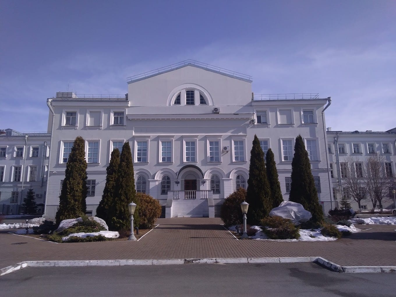 A white neoclassical building of Kazan State Medical University with conifers and winter snow