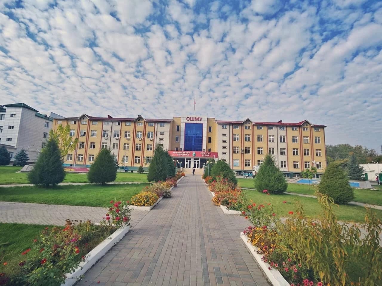 The Osh State University main academic building under a blue sky