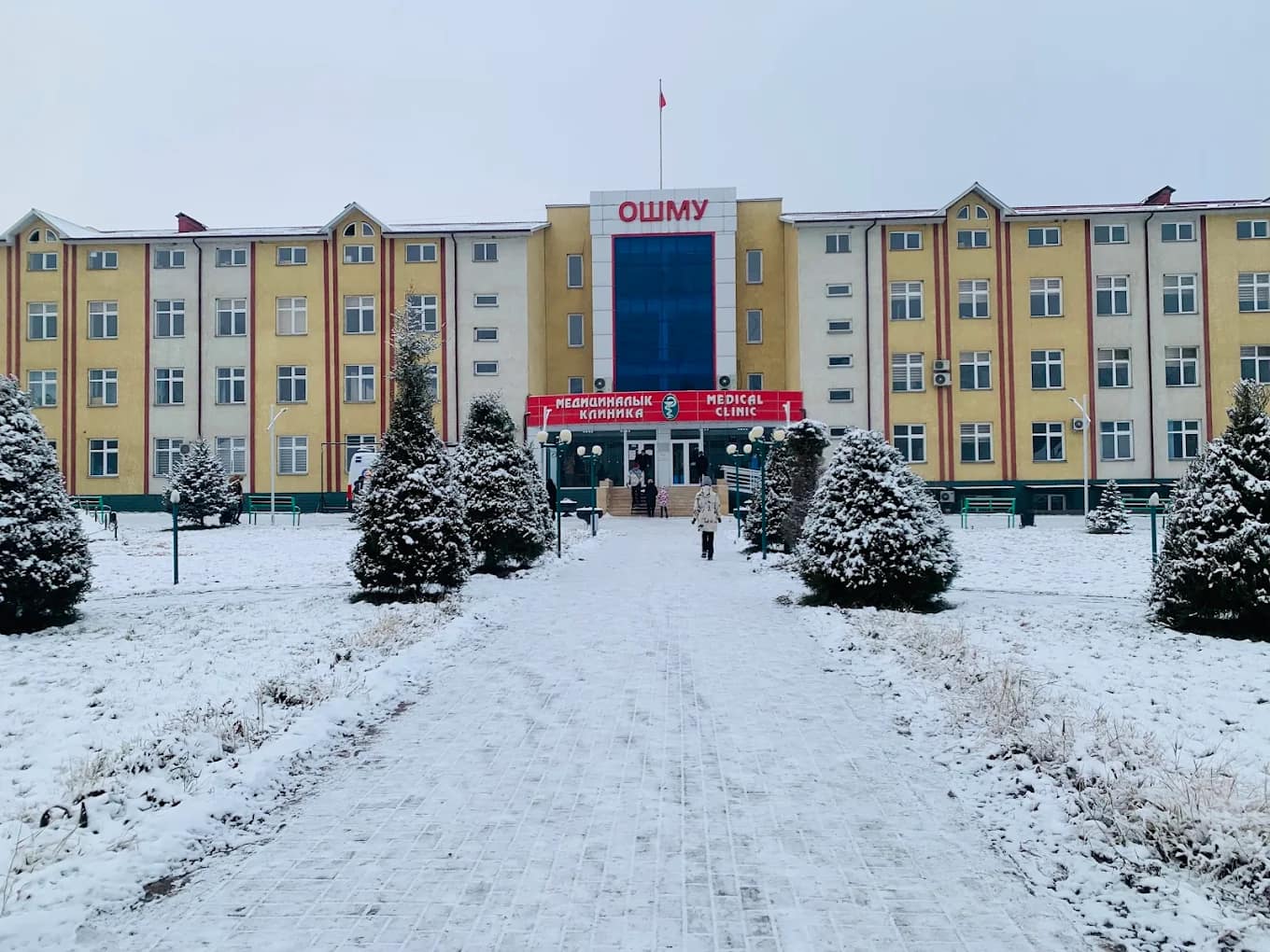 The main building of Osh State University with the ОшМУ sign, seen in winter