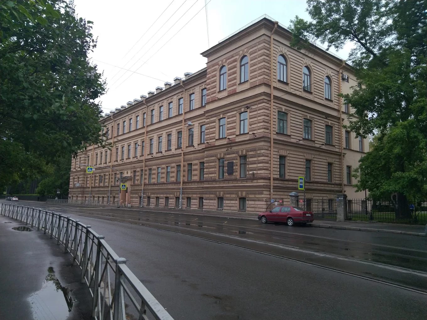 The long historic building of Pavlov First Saint Petersburg State Medical University, the former Women's Medical Institute, on a rain-wet street in St Petersburg