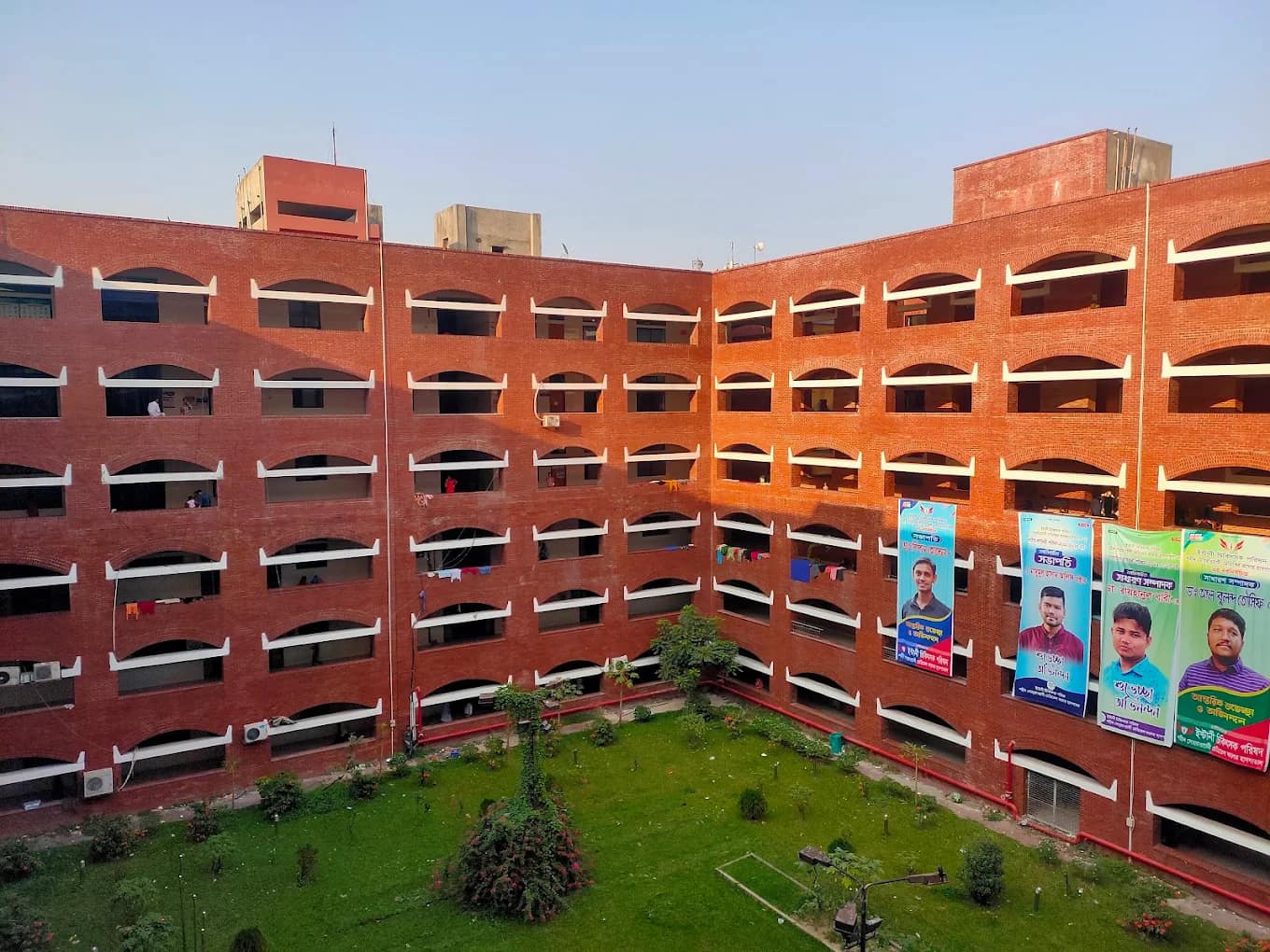 Red-brick academic and residential block of Shaheed Suhrawardy Medical College around a green courtyard