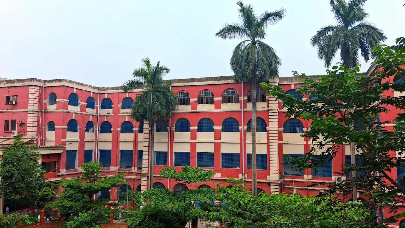 Historic red college building of Sir Salimullah Medical College framed by palm trees