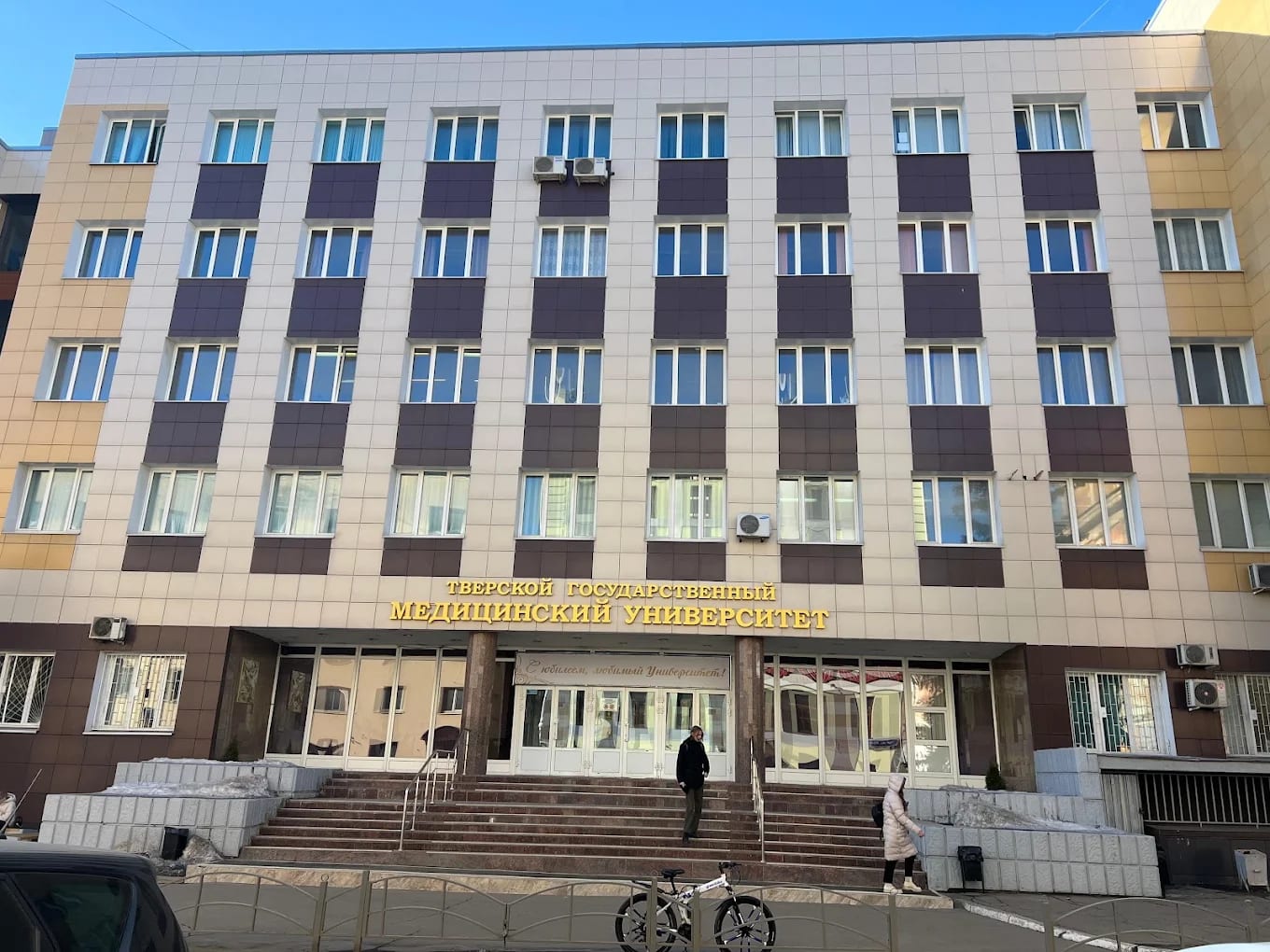 The main entrance of Tver State Medical University with its gold Russian signage, snow banked beside the steps