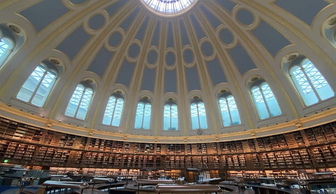 Interior of a historic circular domed library reading room with tiered bookshelves