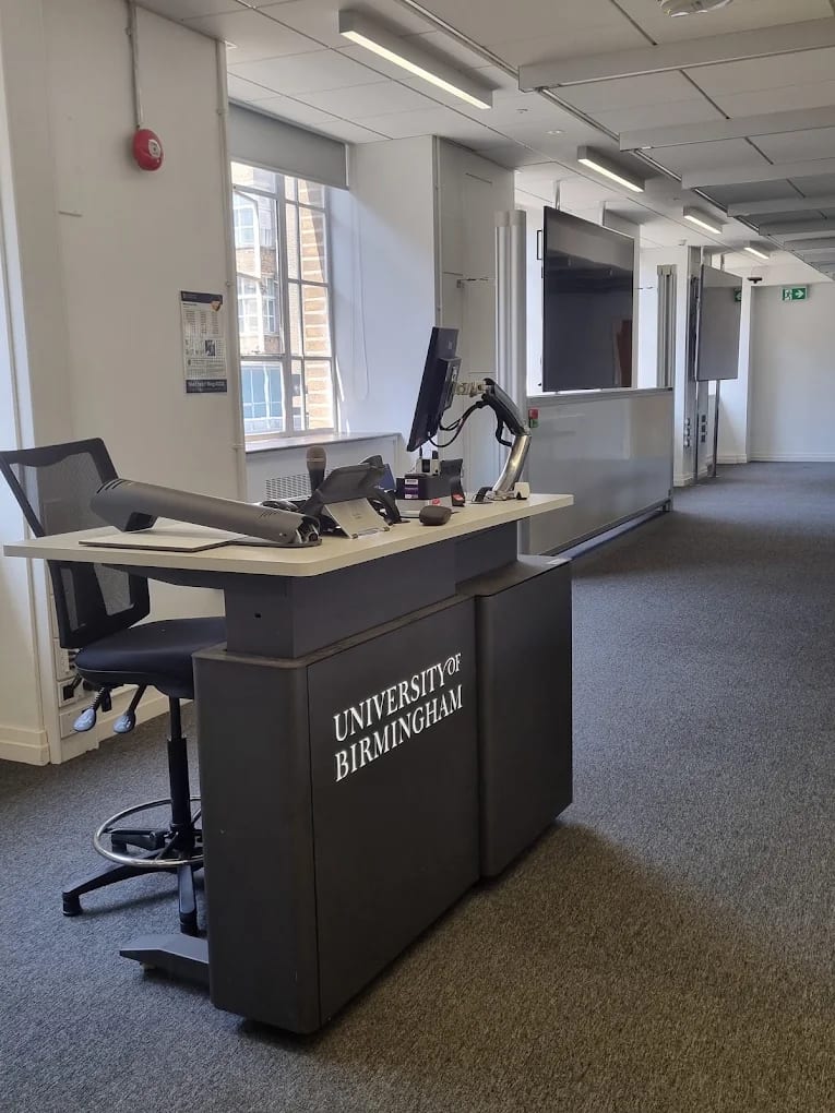 A University of Birmingham teaching space with a branded lectern and screens