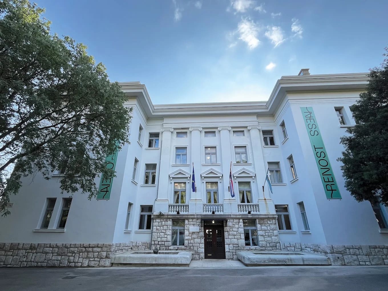 A white neoclassical University of Rijeka building flying the European Union and Croatian flags, Rijeka, Croatia