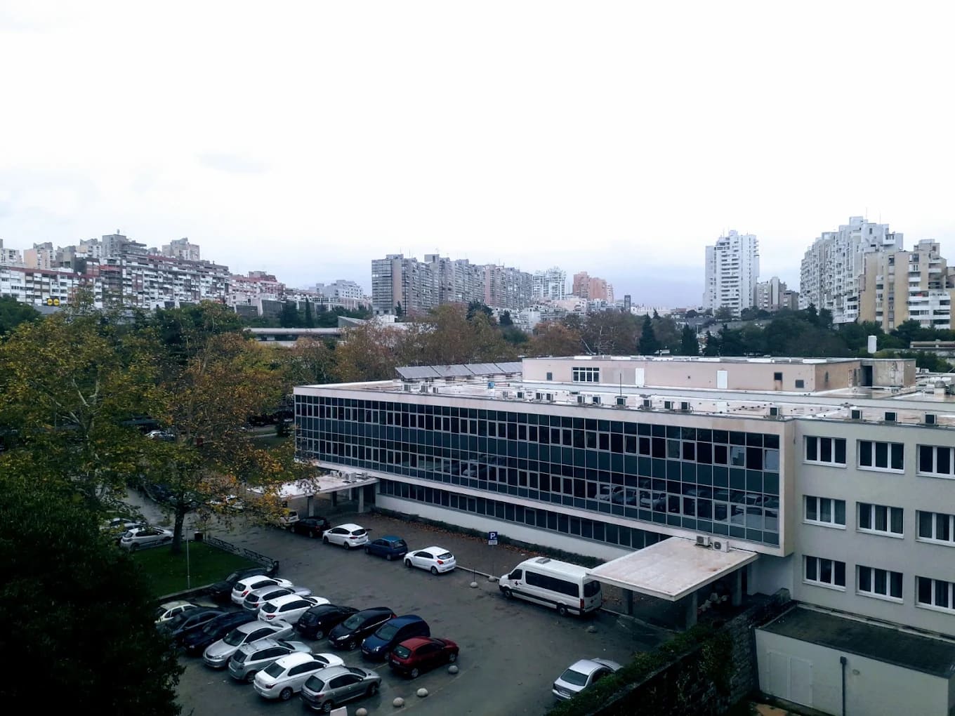 A clinical building with an ambulance in the University Hospital of Split area, with the city's hillside apartment blocks behind, Split, Croatia