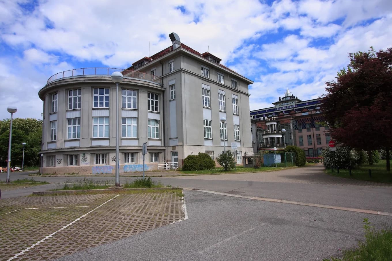 Grey heritage building with a rounded rotunda wing beside a decoratively tiled building on the Šalata medical campus, Zagreb