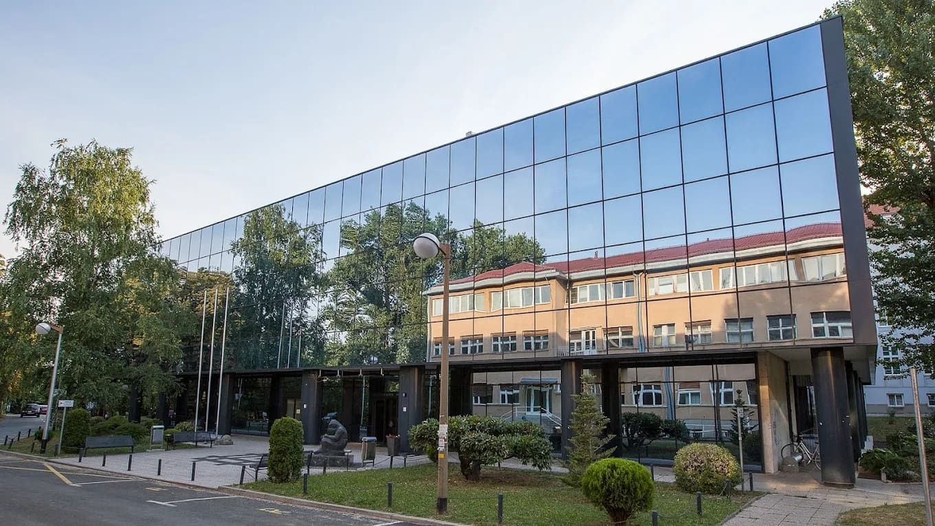 Modern glass-fronted building with a statue outside on the Šalata medical campus of the University of Zagreb School of Medicine
