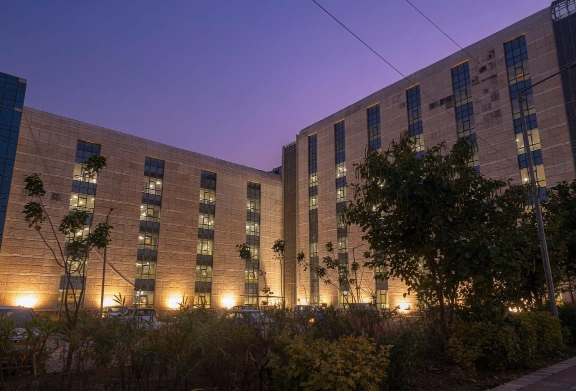 An AIIMS Deoghar academic/hostel block lit up at dusk