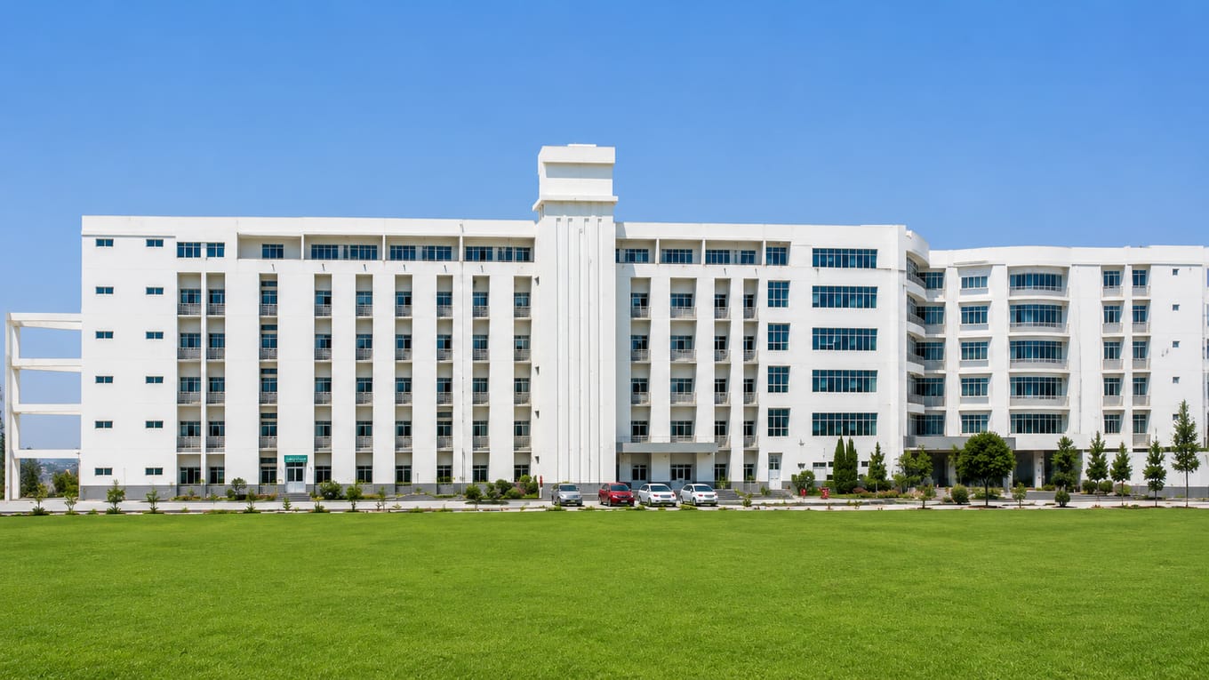 Wide view of the white multi-storey campus building of Al-Falah School of Medical Sciences and Research Centre, Faridabad, behind its front lawn
