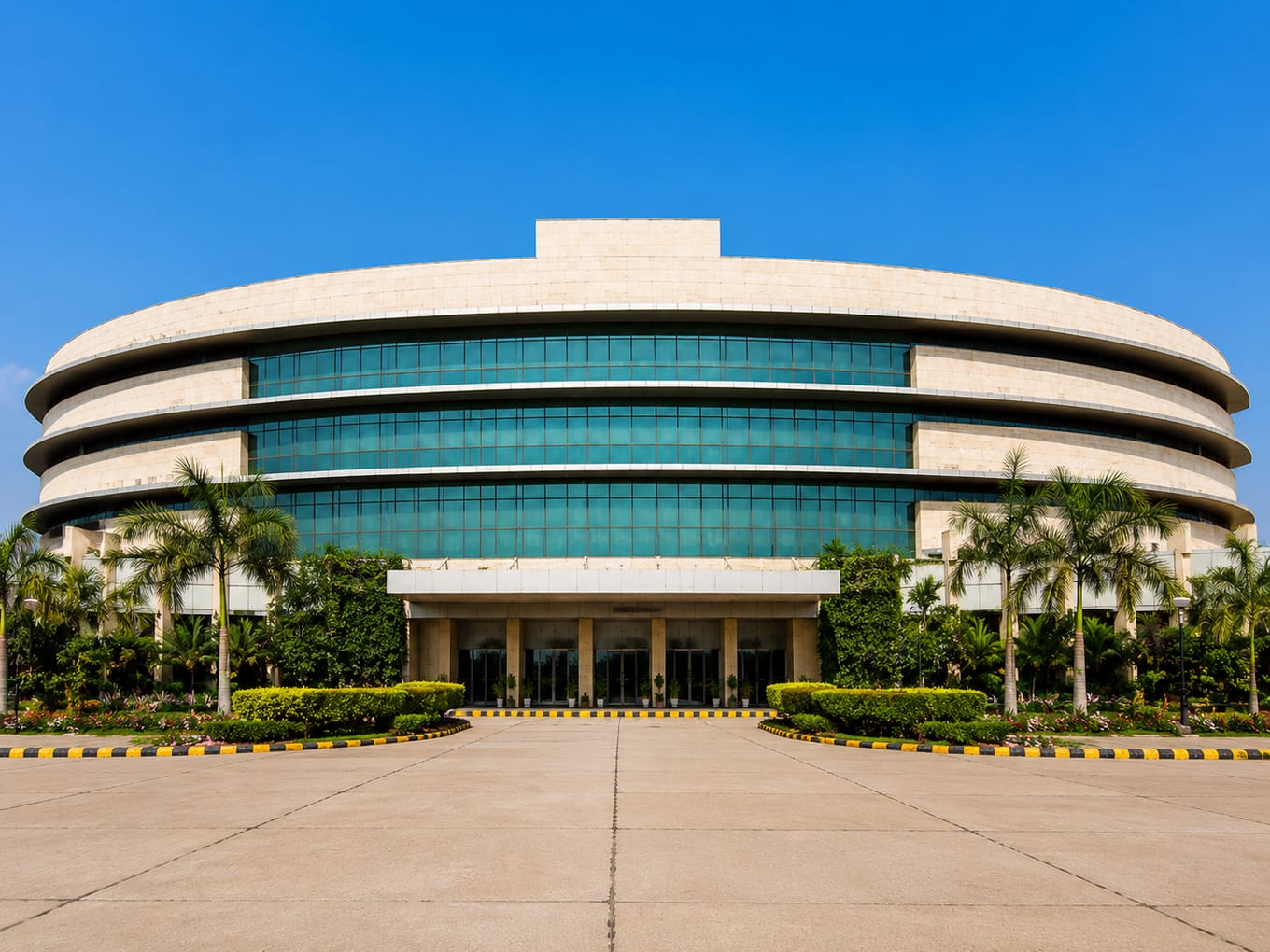 Curved glass-fronted building and palm-lined entrance forecourt at ESIC Medical College and Hospital, Faridabad