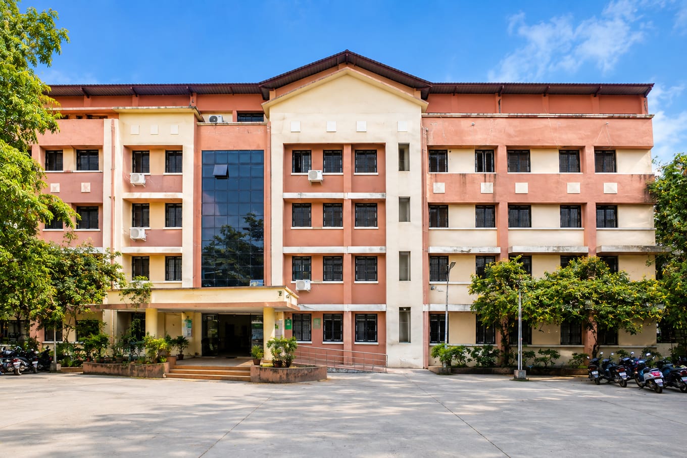 A multi-storey campus building at Government Medical College, Akola, fronted by a tree-lined courtyard