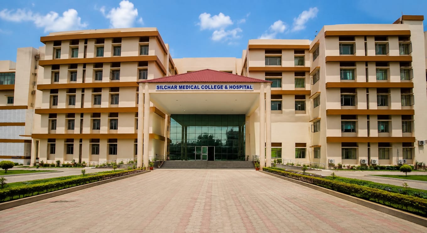 Wide front view of the Silchar Medical College & Hospital main building in Silchar, its name signed above the glass entrance